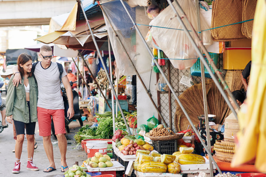 Pareja de turistas explorando un mercado callejero local, representando las experiencias gastronómicas auténticas en un diseño de viajes a medida a China.